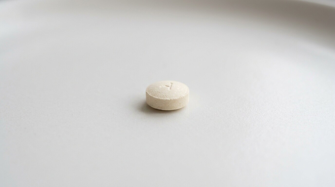 Close-up of a single round oral antifungal tablet resting on a neutral surface